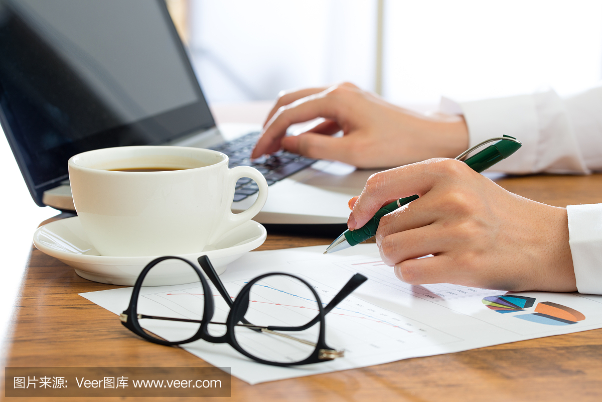 女商人使用笔记本电脑,在办公桌上写作